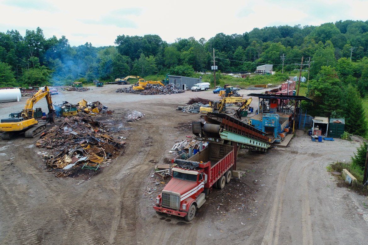 A conveyer belt lifts materials into a dump truck at a scrap yard.